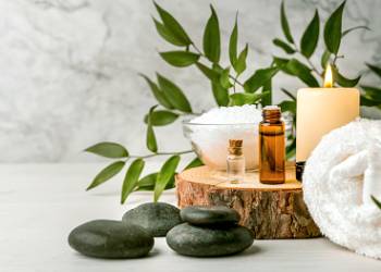 beauty treatment items for spa procedures on white wooden table. massage stones, essential oils and sea salt. copy space